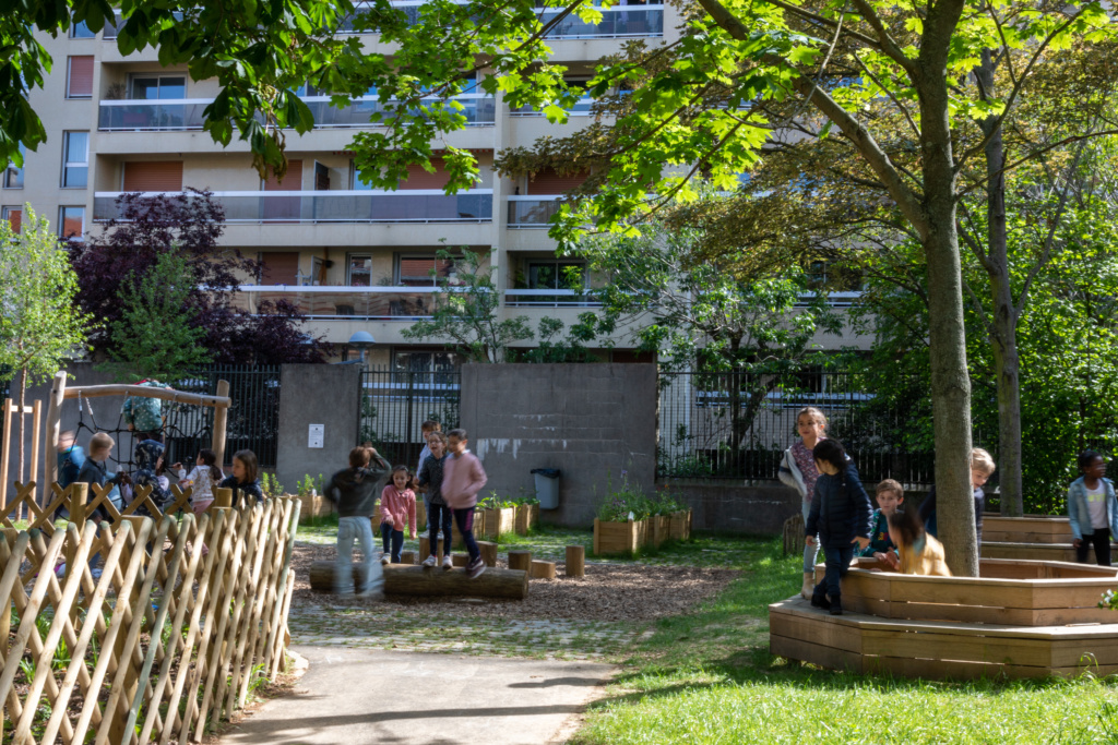 Des grumes et des bancs en tour d'arbre permettent aux enfants de profiter de l'ombre des arbres existants.