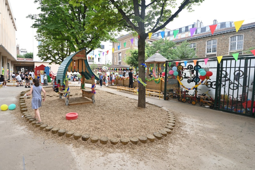 Cour de maternelle - Cabane en bois dans la zone de copeaux centrale et asphalte en périphérie pour la circulation des vélos