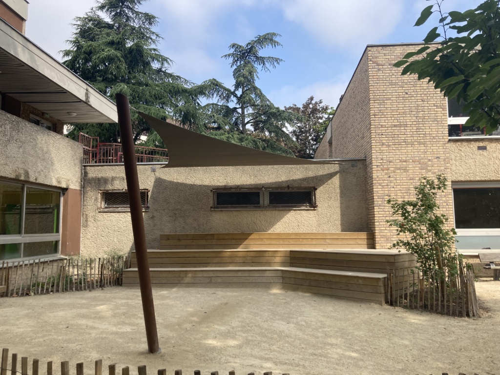 Espace pour faire classe dehors avec des gradins en bois et une toile tendue