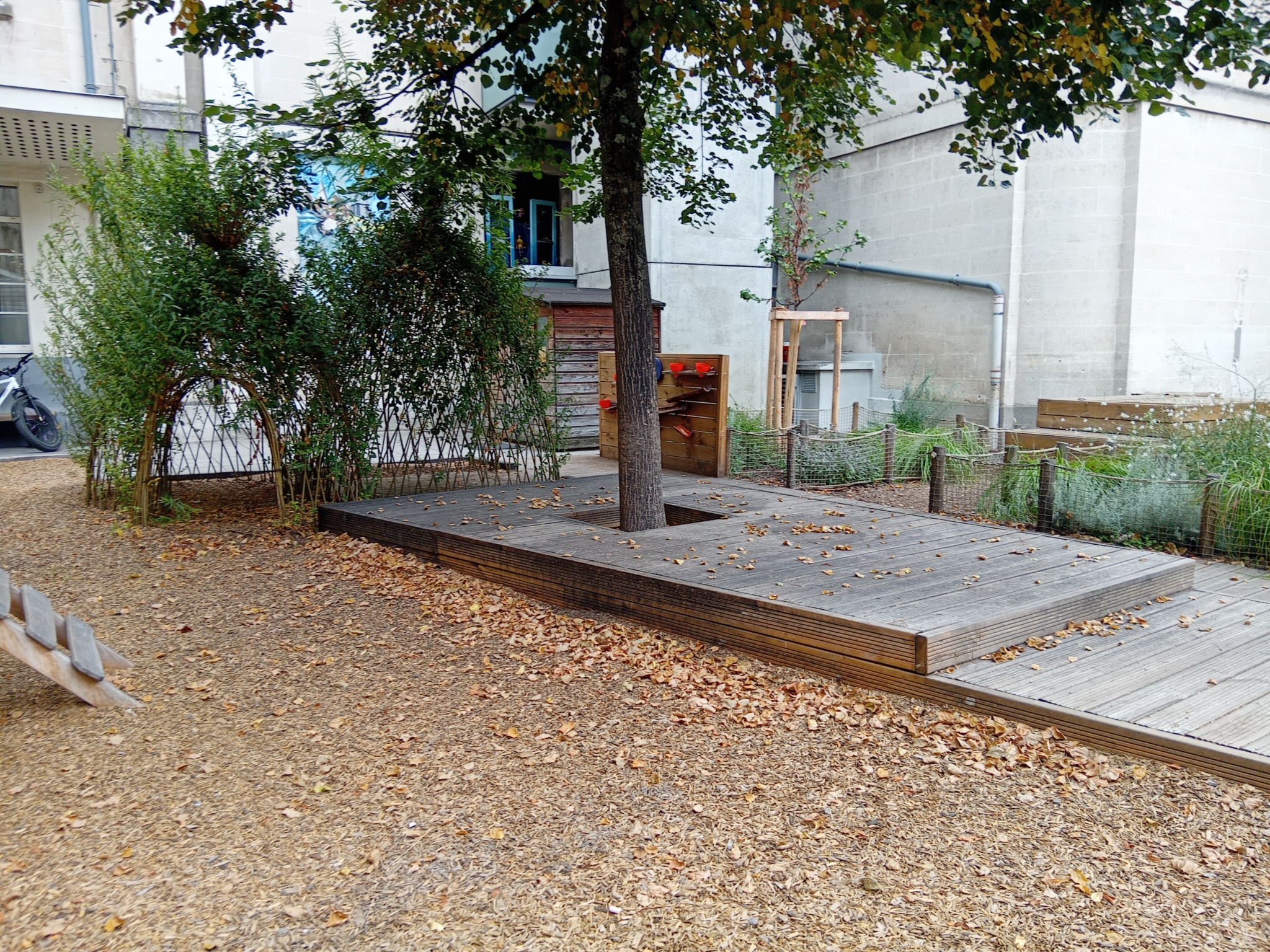 Cour maternelle. Cabanes en osier vivant côté aire de jeux