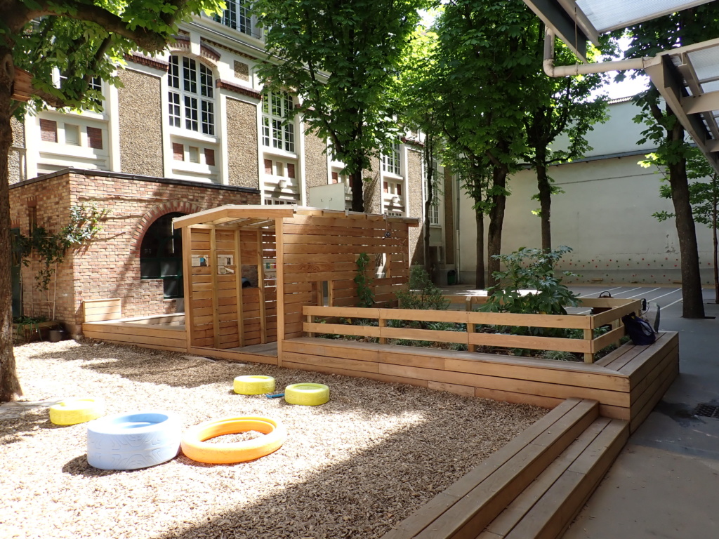 La transition entre les deux espaces avec l'espace classe dehors, la cabane et le massif planté 