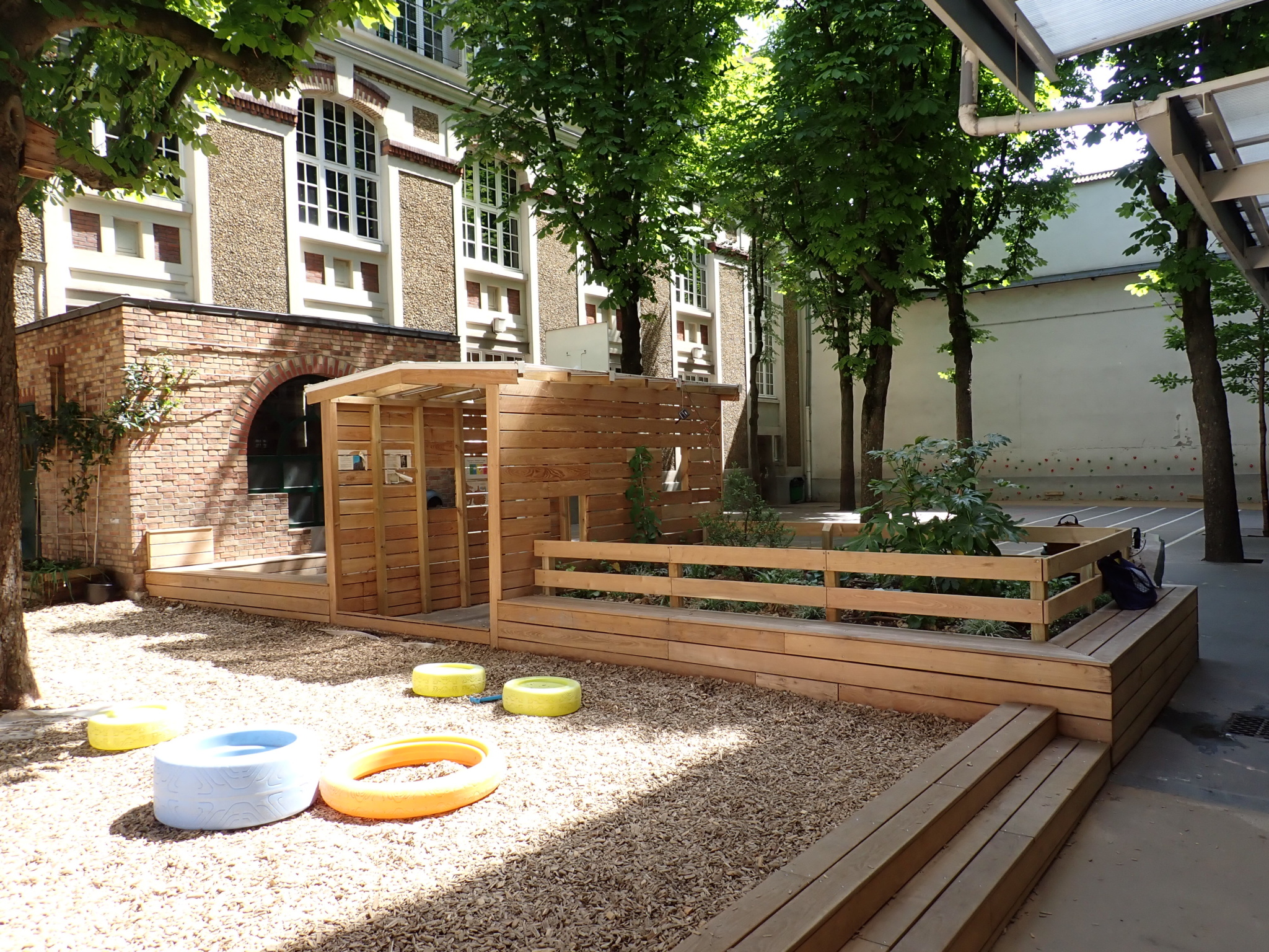 La transition entre les deux espaces avec l'espace classe dehors, la cabane et le massif planté 